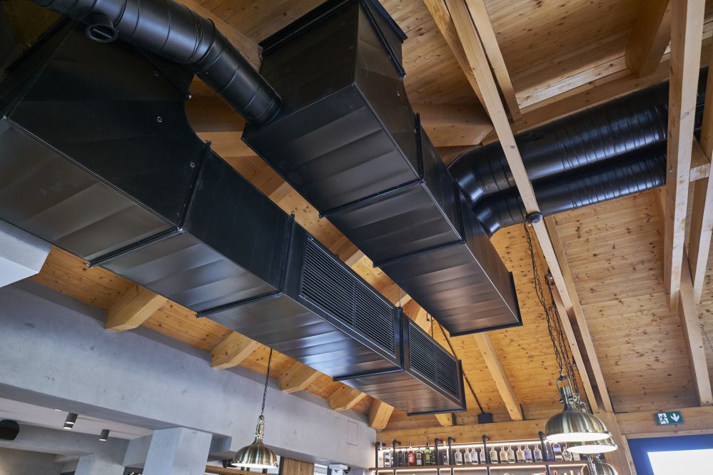 Metal air conditioning piping on the ceiling to tie in with the retro, rustic interior design.