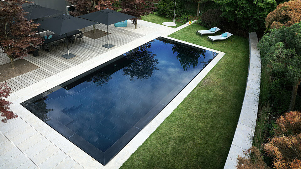 Dark colored luxury pool view from above with green and maroon plants