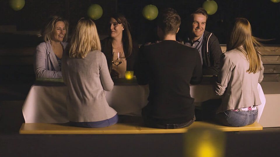 Group of friends sitting around an outdoor table at night.