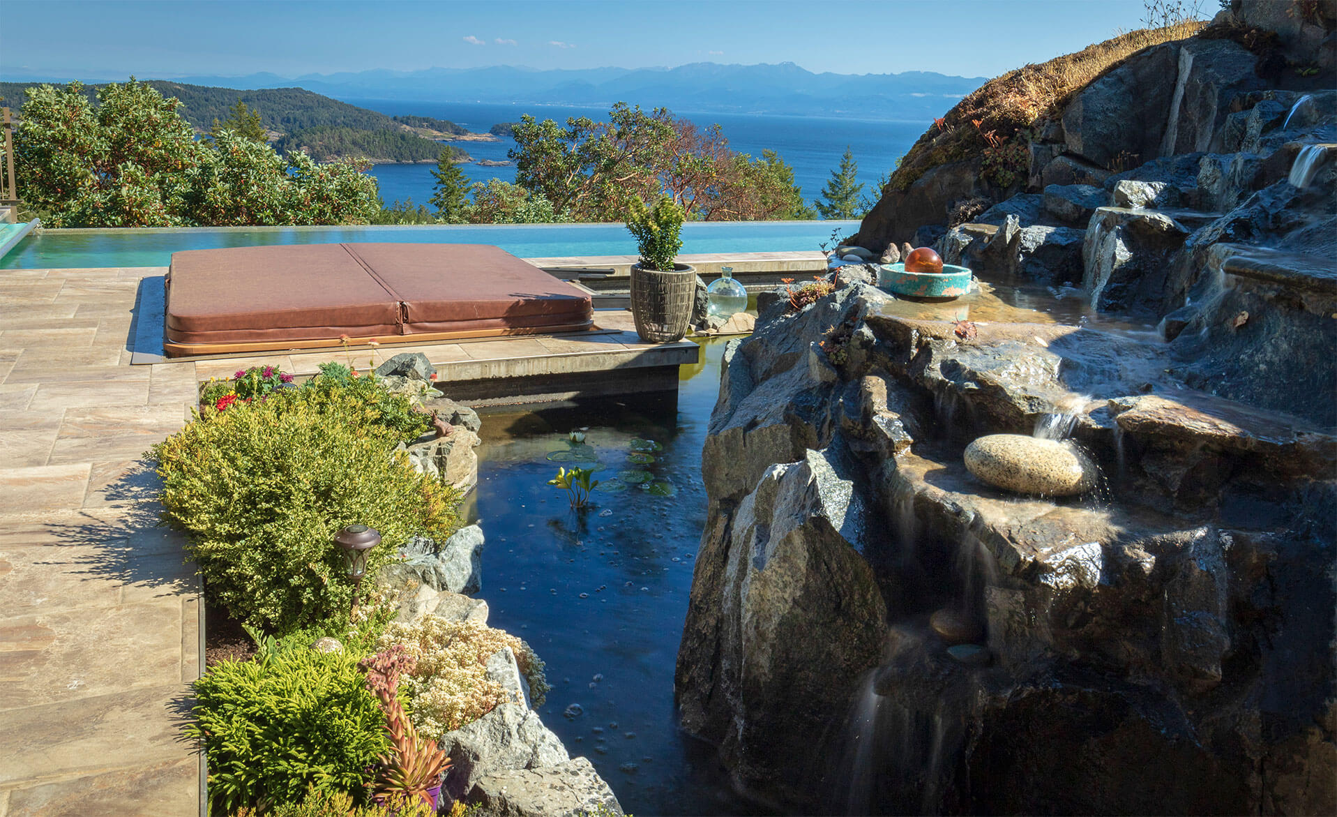 Outdoor hot tub, waterfall and pool overlooking mountains.