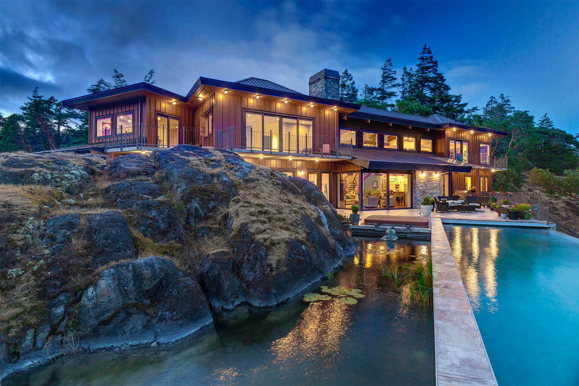 Back of Olympic Panorama home lit at dusk with pool and pond