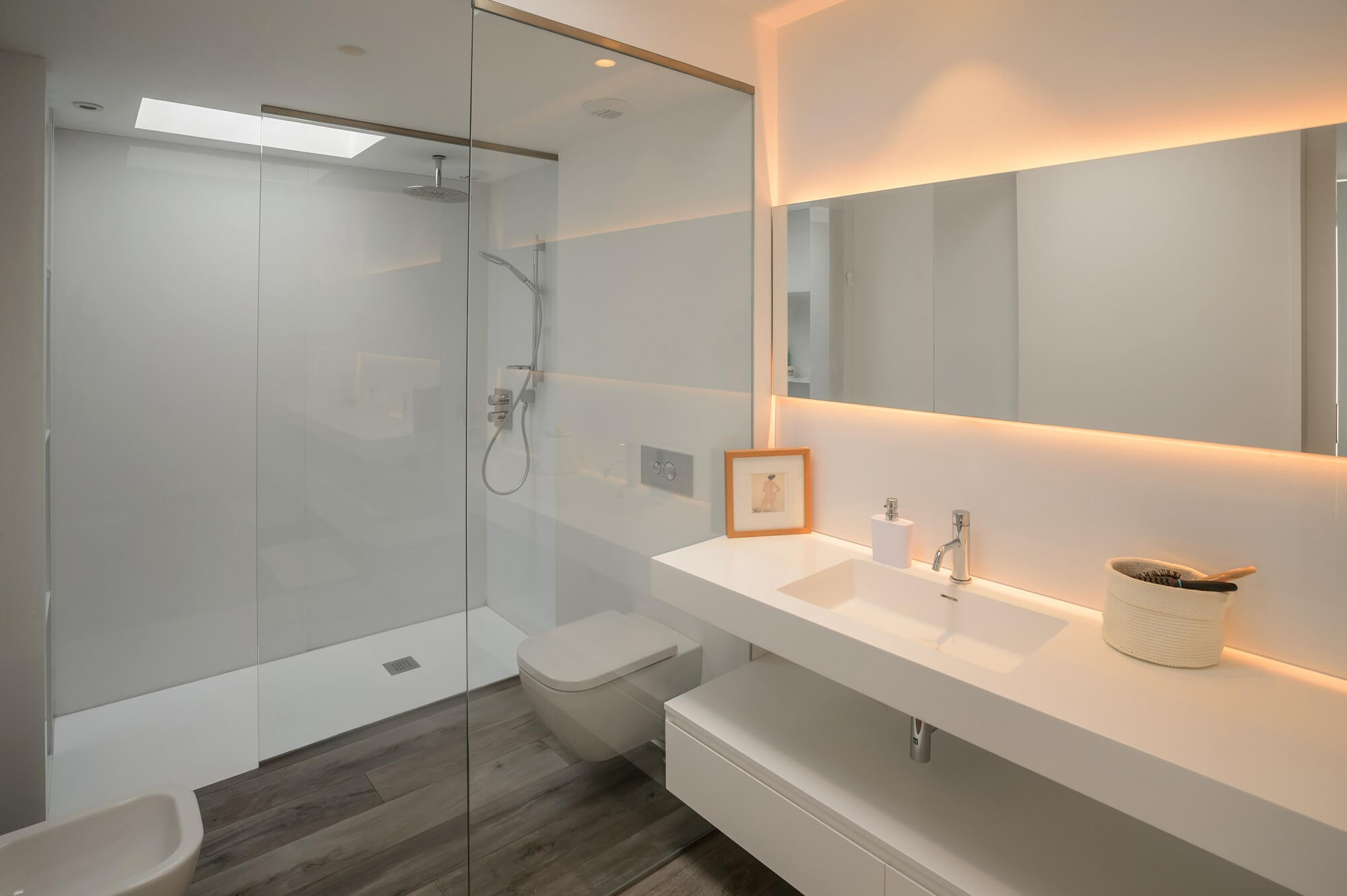 bílá koupelna v minimalistickém stylu s velkým zrcadlem podsvíceným LED páskem
