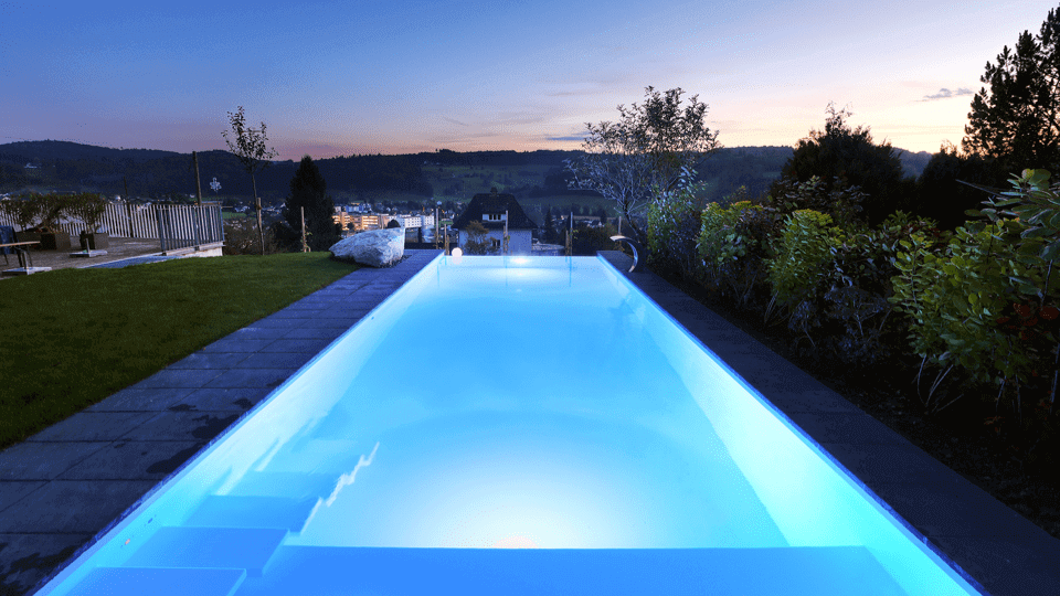 Atmosphärisch beleuchteter Pool im Garten