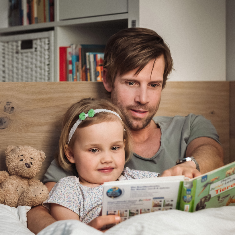 Otec číta dcére v posteli knihu