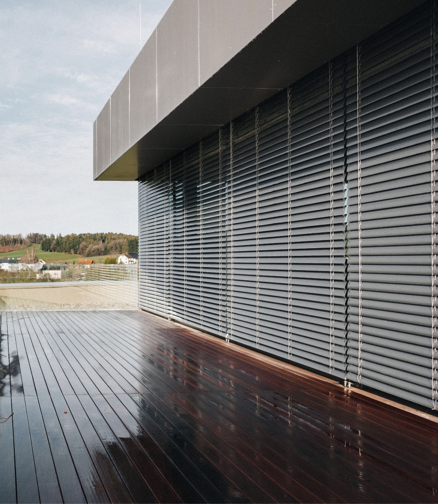 Вигляд ззовні на будівлю з опущеними зовнішніми жалюзі з інтелектуальним керуванням.