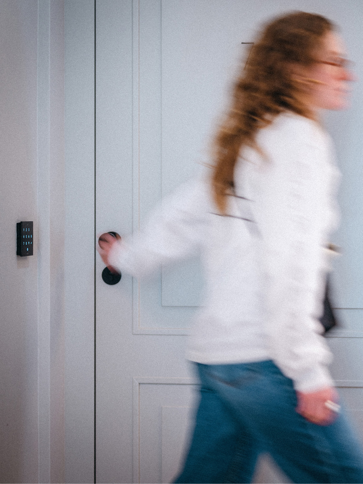 Жінка відкриває двері з цифровою панеллю контролю доступу.