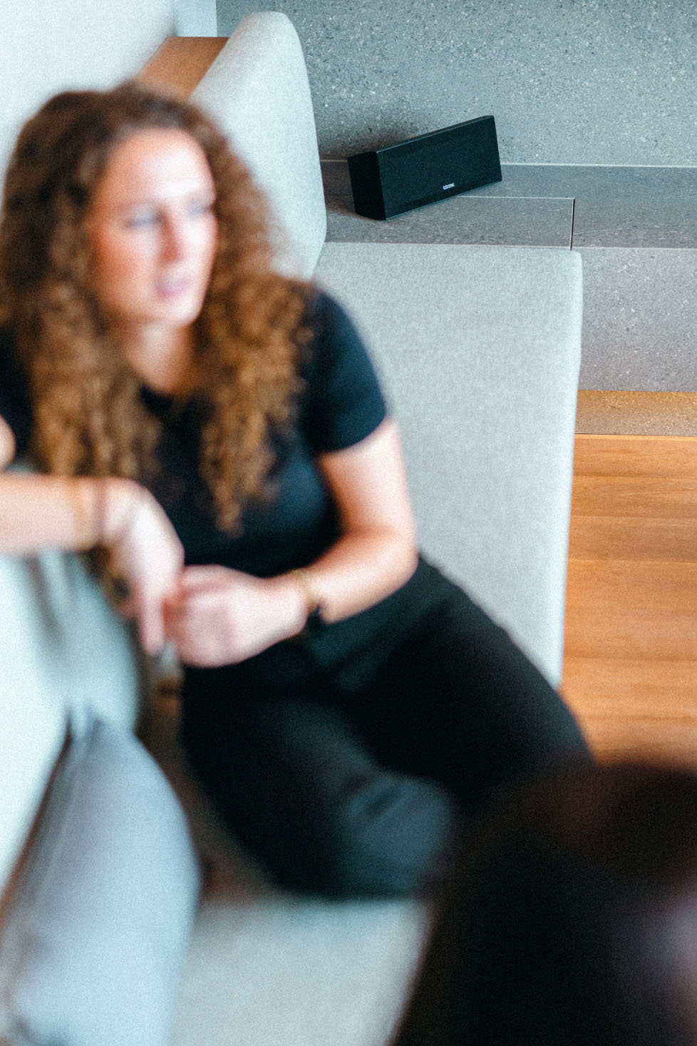 Жінка сидить на дивані у вітальні та насолоджується музикою.