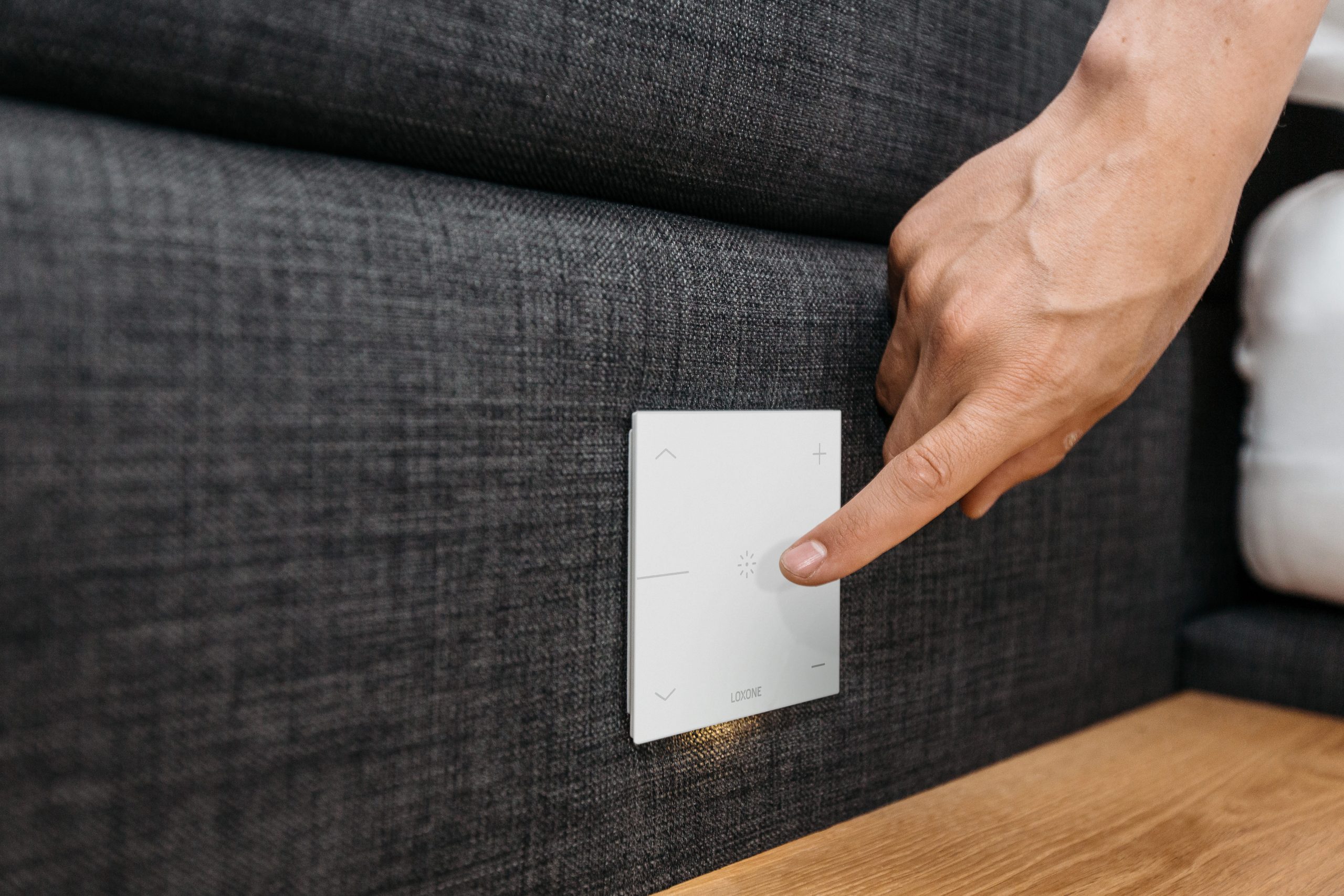 Рука торкається білого LOXONE Touch Pure біля узголів'я ліжка
